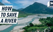 A photograph of the Vjosa river with a high mountain seen in the background and village in the bottom right corner. Caption reads "How to save a river"