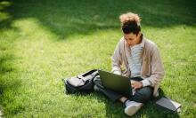 Student on lawn using laptop