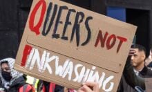 A pro-Palestinian protester from the Free Palestine Coalition holds up a sign criticizing Israeli 'pinkwashing' during a march through central London.