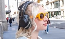 young woman in yellow sunglasses wearing Sony headphones on city street