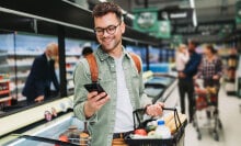 A person looking at their phone while standing in a grocery store.