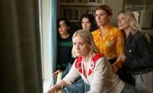 A group of women in a room look out of a window.