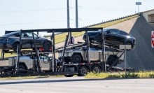 Tesla vehicles, including Cybertrucks, loaded on a transport that seems to be going nowhere.