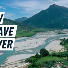 A photograph of the Vjosa river with a high mountain seen in the background and village in the bottom right corner. Caption reads "How to save a river"