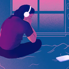 A young person listens to headphones on their bed.