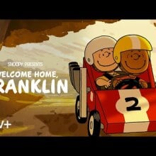 Charlie Brown and Franklin Armstrong ride in a soapbox car through the woods.