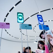 A woman takes a photo of iPhone 16 display models