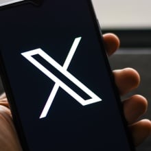 A person looks at X on their cell phone.