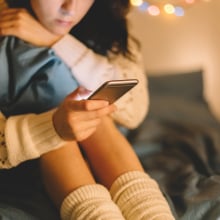 Girl looks at phone in a seated position. 