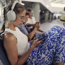 girl on phone in airport terminal wearing sony wh-1000xm5 headphones