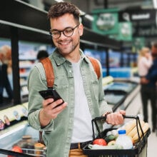 A person looking at their phone while standing in a grocery store.