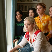 A group of women in a room look out of a window.