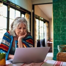 A woman peers at her laptop.