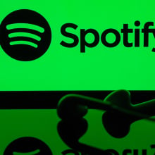 A screen displaying "Spotify" on a green backdrop with headphones laying in front of it.