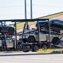 Tesla vehicles, including Cybertrucks, loaded on a transport that seems to be going nowhere.