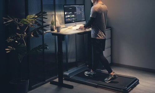 man using iQ Slim Walking Pad at night while working