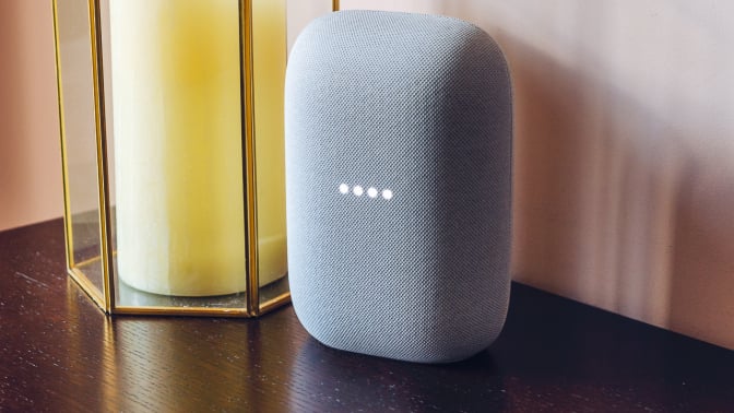 google nest in grey blue on wood table, yellow candle on foreground