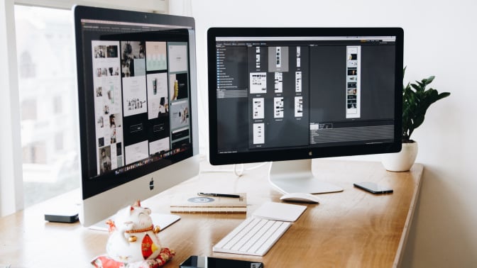 Two computers on desk showing graphic design app