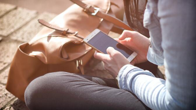 a close-up of a sitting woman typing on a smartphone