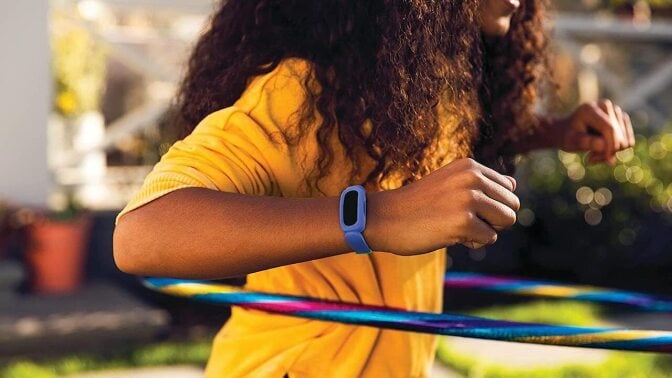 Child hula hooping while wearing blue Fitbit