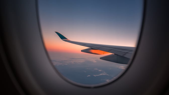 Wing of plane and sunset out window of airplane