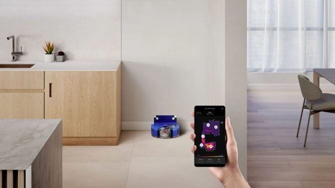 Dyson 360 Vis Nav robot vacuum and dock sitting against wall in kitchen with counter and dining table in peripherals