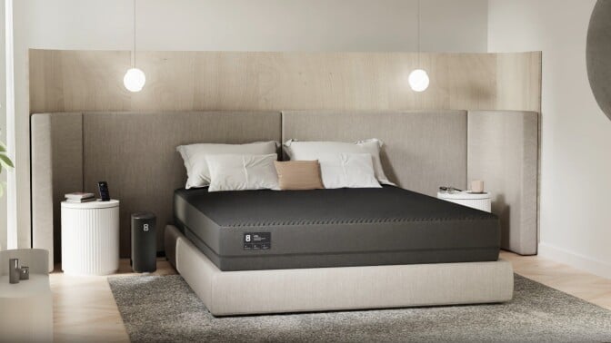 a bed sits in the center of a bedroom with the Eight Sleep Pod 3 cover over the mattress and pillows above the cover