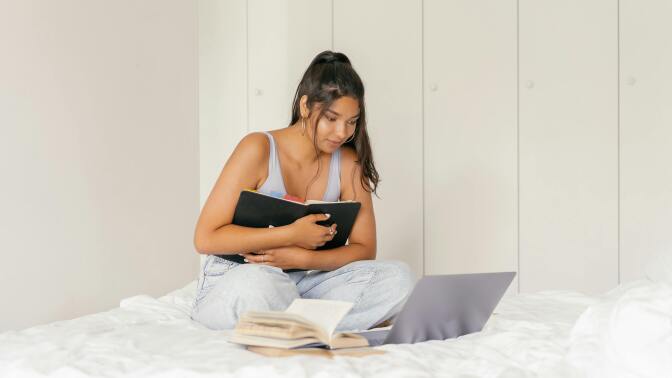 Girl holding laptop on bed