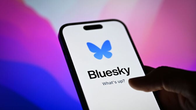 Bluesky app on a smartphone in front of a desktop screen