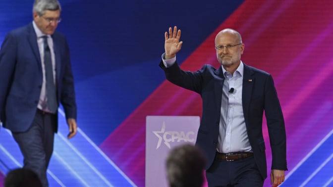 Brendan Carr, waving to the crowd, walks onstage at the annual CPAC meeting. 