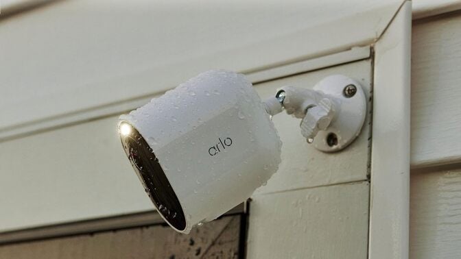 an arlo spotlight security camera affixed to the side of a house