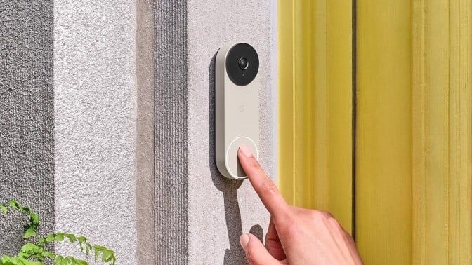 a person's right index finger approaches touching the google nest video doorbell that's affixed next to a home's front door