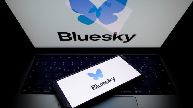 A glowing laptop screen and phone screen both display the Bluesky logo.