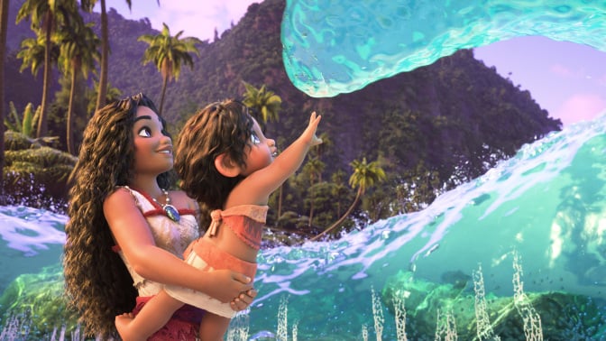 A still from "Moana 2" in which Moana holds her little sister up to a friendly wave in greeting.