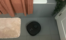 Eufy X10 Pro Omni robot vacuum mopping tile floor in bathroom near shower and bath mats