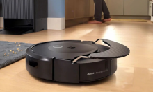 Roomba Combo 10 Max robot vacuum mopping hardwood floor with AutoWash dock in background