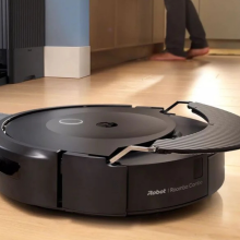 Roomba Combo 10 Max robot vacuum mopping hardwood floor with AutoWash dock in background