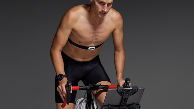 A man uses an exercise bike with a Garmin heart rate monitor.