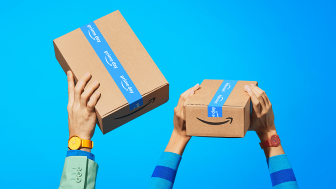 hands holding up Amazon Prime packages against blue background