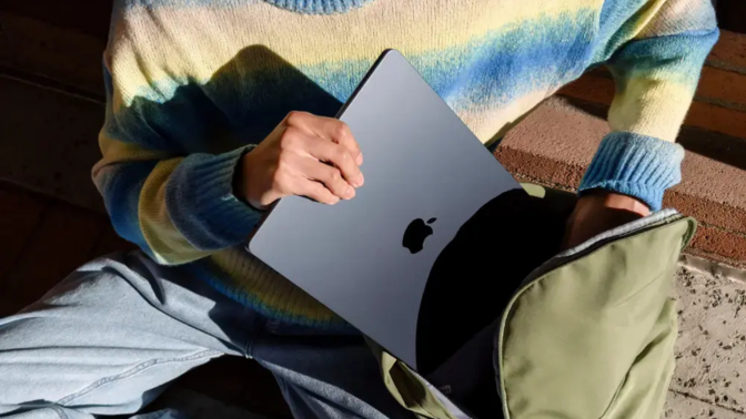 A person putting a MacBook Air into a backpack